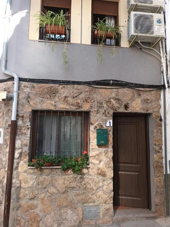 a stone building with a door and windows and potted plants at La Tijera in Candeleda