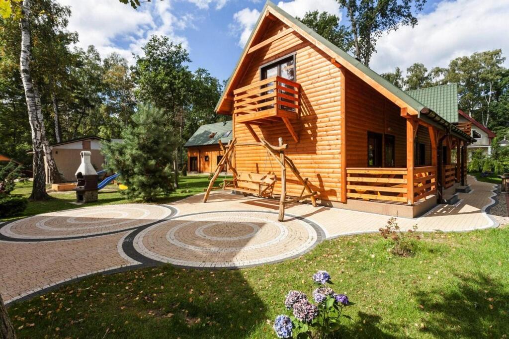 a small log cabin with a garden and a house at Holiday Resort in Pobierowo for 6 persons in Pobierowo