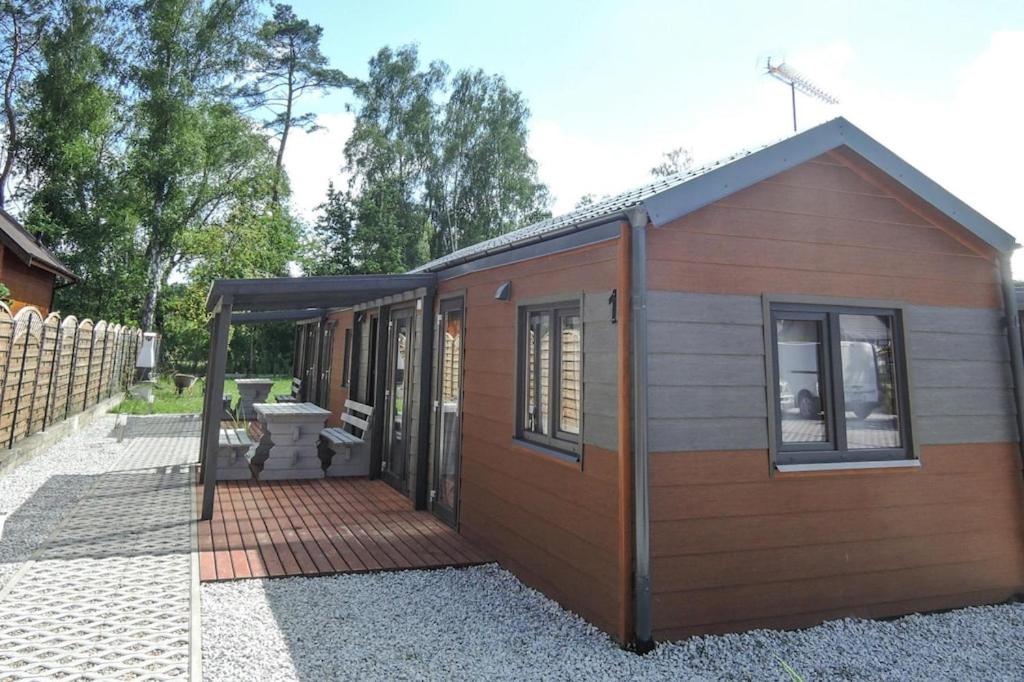 eine kleine Hütte mit einer Veranda und einer Terrasse in der Unterkunft Bungalows, Dziwnow in Dziwnów