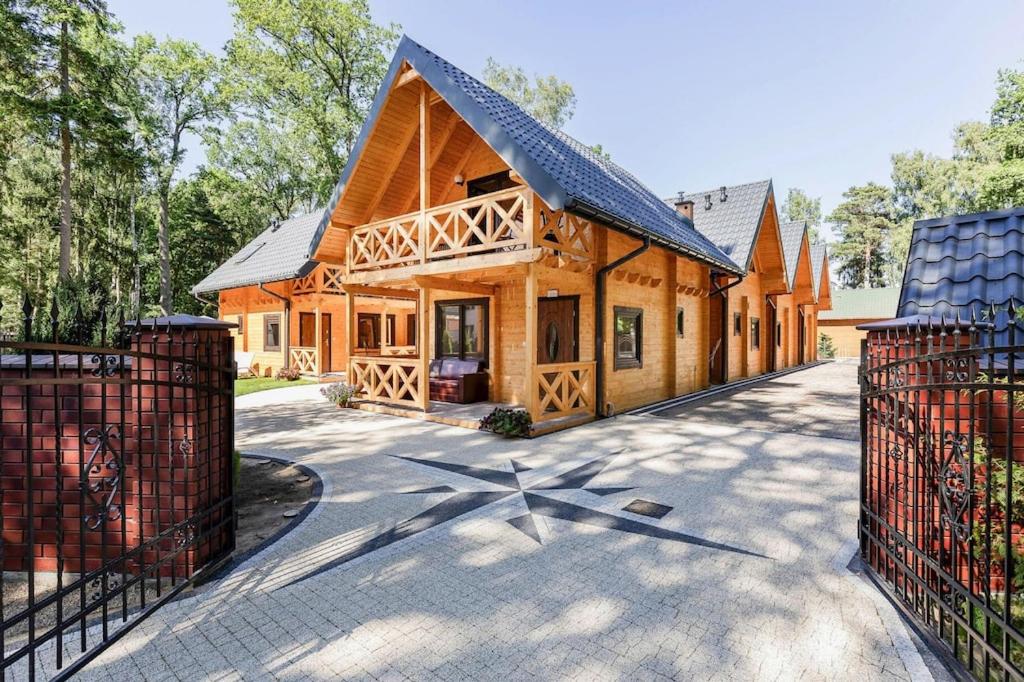 a large wooden house with a fence in front of it at Holiday complex, Pobierowo in Pobierowo