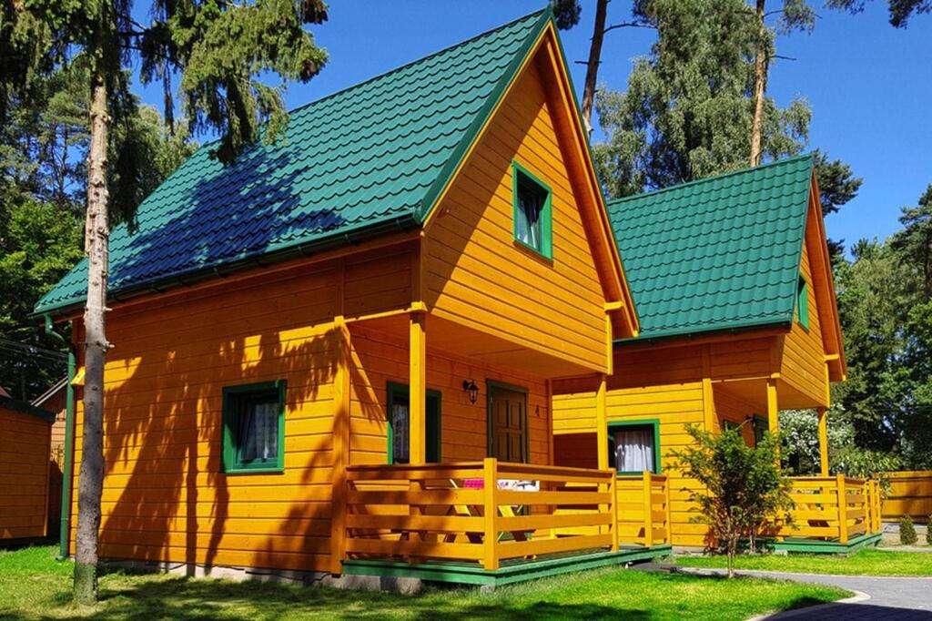 a yellow house with a green roof at Holiday homes, Pobierowo in Pobierowo