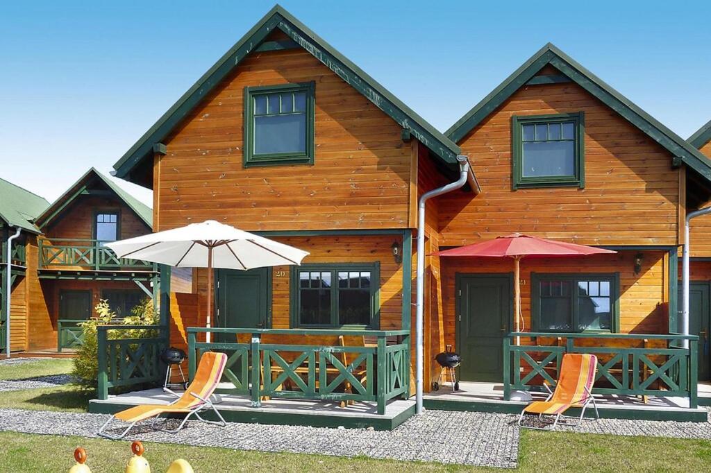 uma casa de madeira com duas cadeiras e um guarda-sol em Terraced Houses, Sarbinowo em Sarbinowo