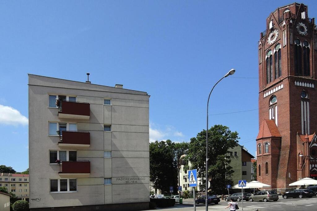 a building with a clock tower next to a street at Apartment in Swinoujscie near Baltic Beach in Świnoujście
