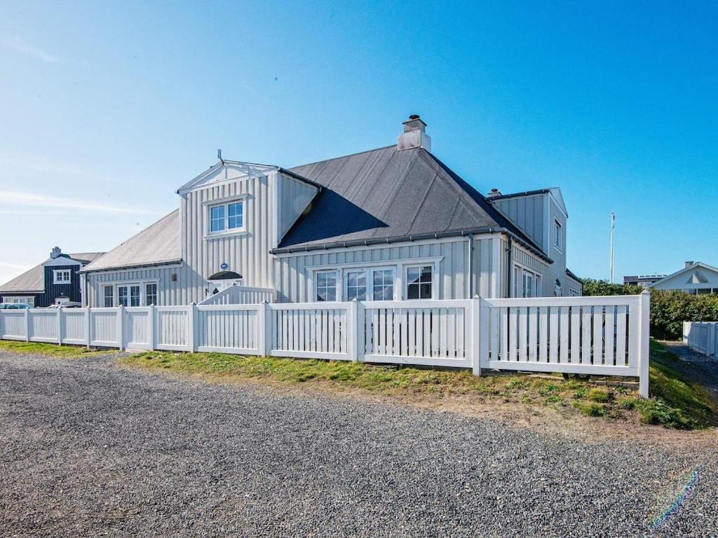 a white fence in front of a white house at 6 person holiday home in Ringk bing in Ringkøbing