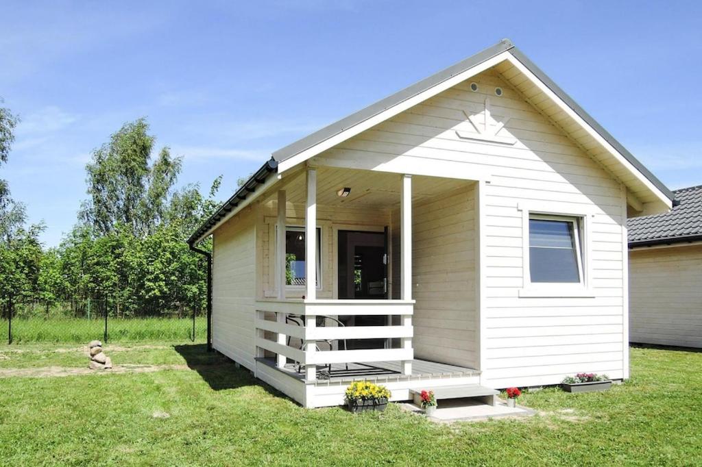 a small white house with a porch in a yard at Holiday complex, Kolczewo in Kołczewo