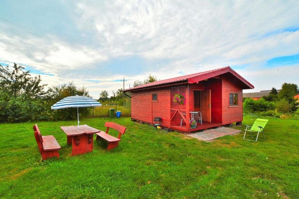 a small red house with a picnic table and an umbrella at holiday home, Rusinowo in Rusinowo