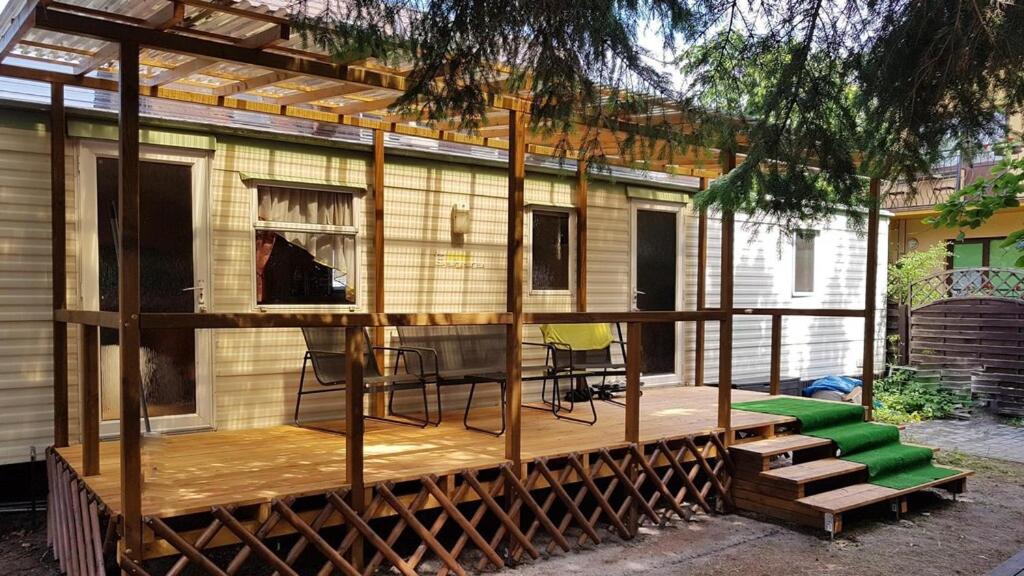 ein Haus auf einer Holzterrasse mit einer Veranda in der Unterkunft Bungalow, Mrzezyno in Mrzeżyno