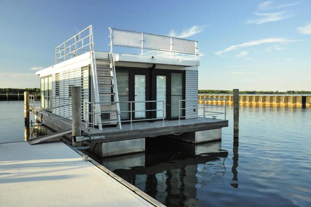 uma pequena casa numa doca na água em Hausboot Floating House Leni in Ribnitz-Damgarten em Ribnitz-Damgarten