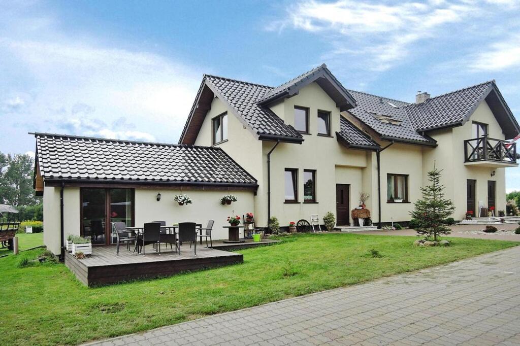 een groot wit huis met een tafel en stoelen bij Semi-detached big house for 16 persons by the lake in Troszyn in Troszyn