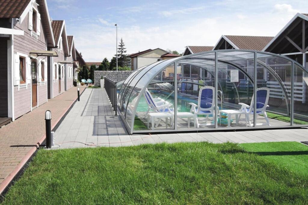 a glass house with chairs in it in a yard at Holiday complex with the pool and volleyball in Miedzyzdroje in Międzyzdroje