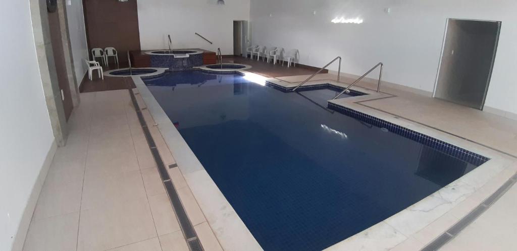 a large swimming pool with blue water in a room at Flat no APART-HOTEL Cavalinho Branco com PISCINA AQUECIDA 1D8 in Águas de Lindoia