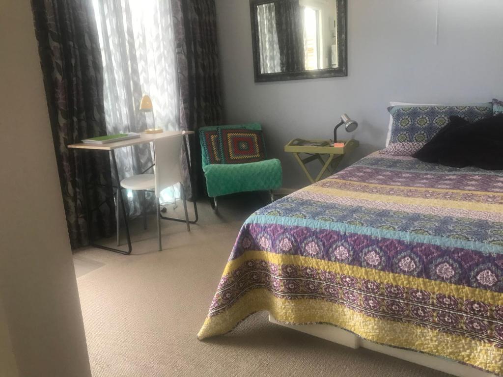 a bedroom with a bed and a chair and a table at Cosy Caversham Retreat in Dunedin