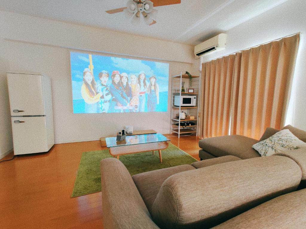 River Sky Hakata في فوكوكا: غرفة معيشة مع أريكة ولوحة كبيرة على الحائط