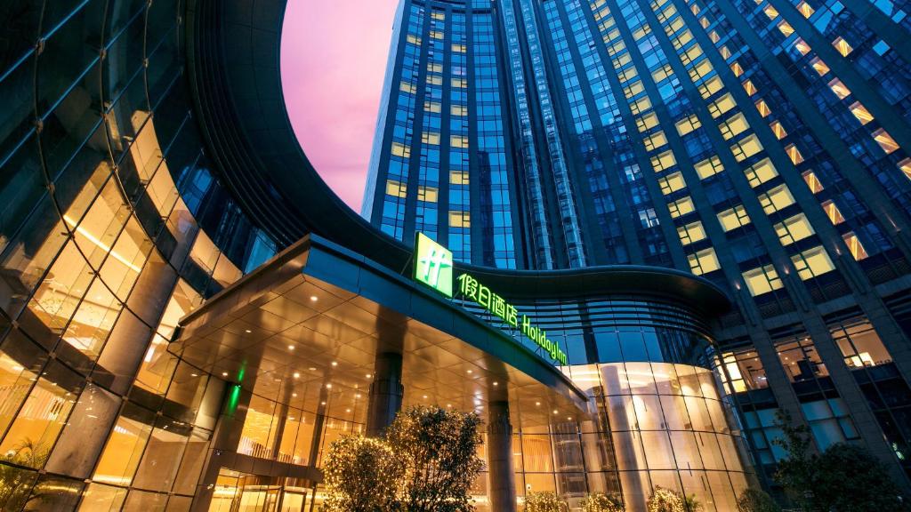 Holiday Inn Hangzhou Gongshu by IHG في هانغتشو: مبنى كبير مع لافتة أمامه