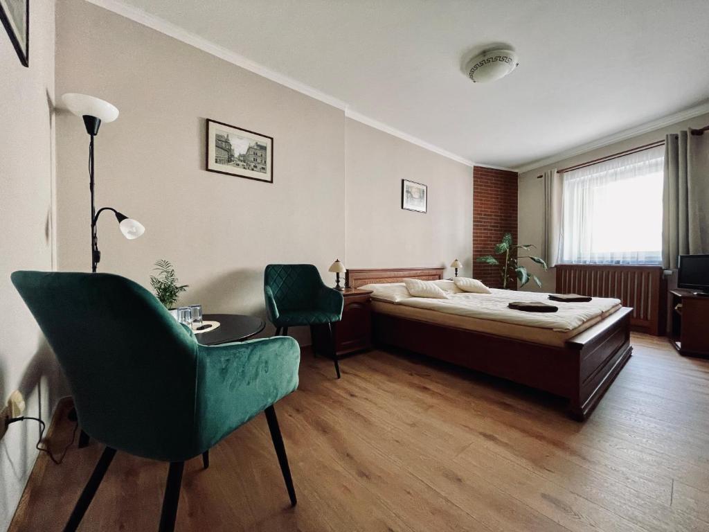 a bedroom with a bed and a green chair at Pension Silvie in Vlašim