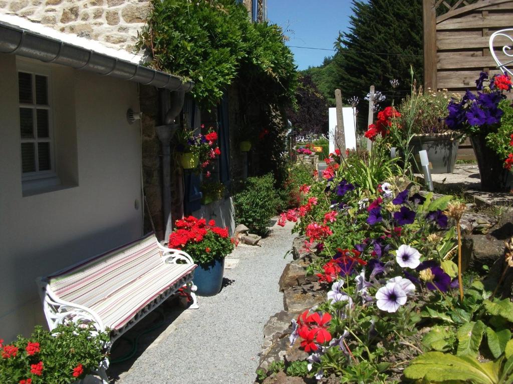 um banco sentado ao lado de um jardim com flores em Au Bon Accueil em Saint-Marcan