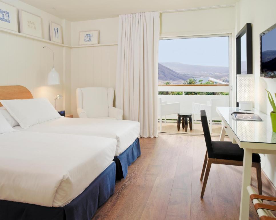 a hotel room with a bed and a table and a desk at Boutique Hotel H10 Big Sur - Adults Only in Los Cristianos