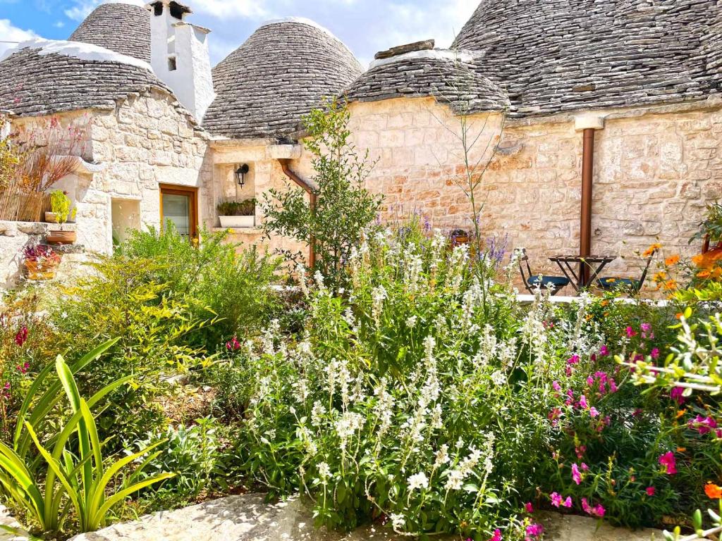 a garden in front of two stone buildings with flowers at Trullo Aprìco in Alberobello