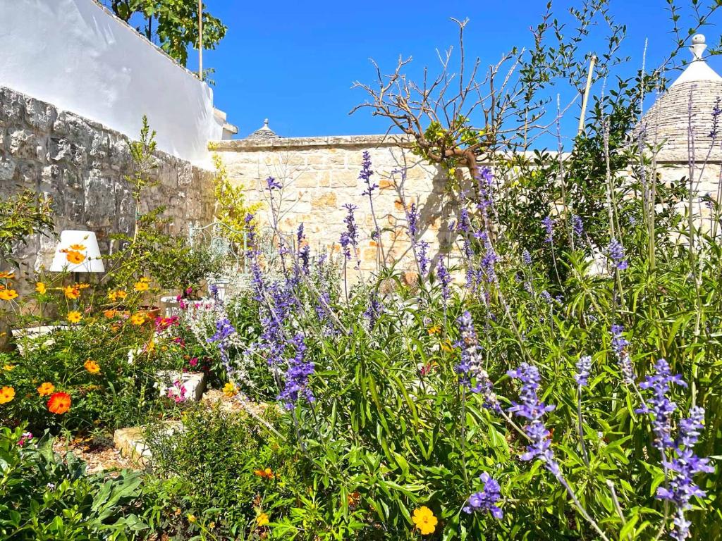 a garden with purple flowers in front of a brick wall at Trullo Aprìco in Alberobello