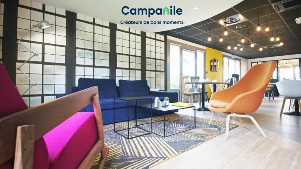 Campanile Hotel Senlis في سونلي: غرفة بها أريكة زرقاء وطاولة وكراسي