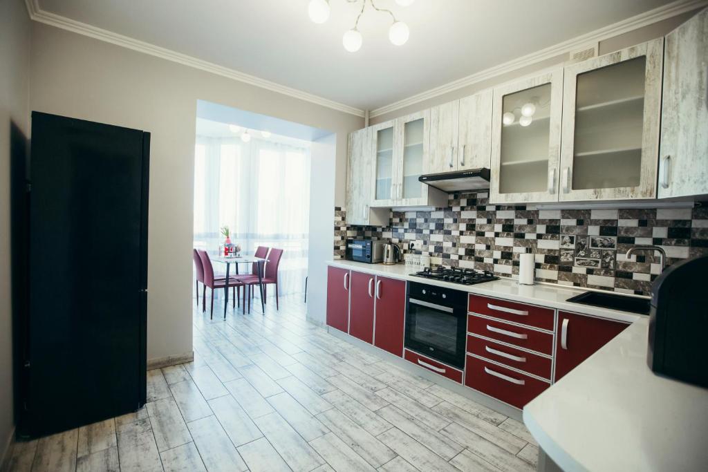 una cucina con armadi rossi e un tavolo con sedie di Atlant apartments a Černivci