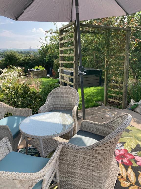 a patio with chairs and tables and an umbrella at Lazy Days Cottage in Barrowford