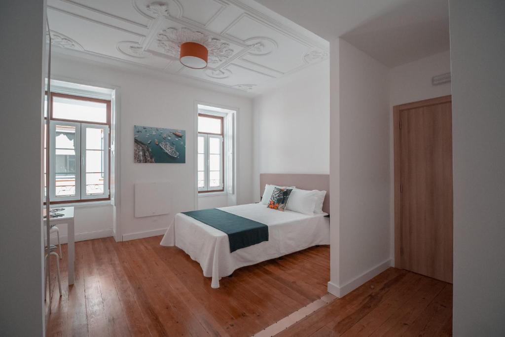 a white bedroom with a bed and two windows at Harbour49 - AVEIRO FLATS & SUITES in Aveiro