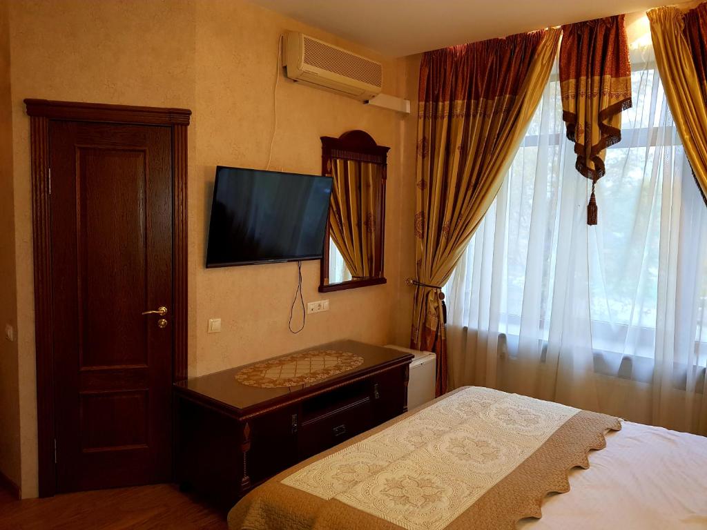 a bedroom with a bed and a television on the wall at Happy Inn Sofiyskaya in Saint Petersburg