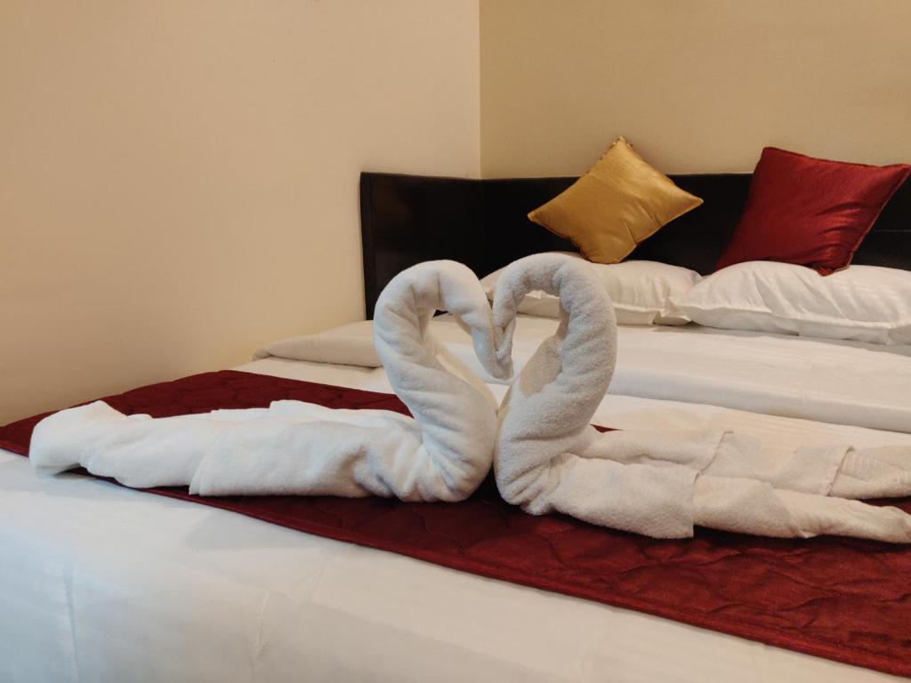 Dos toallas están hechas para parecer cisnes en una cama. en SRI VIGNESH RESIDENCY en Chennai
