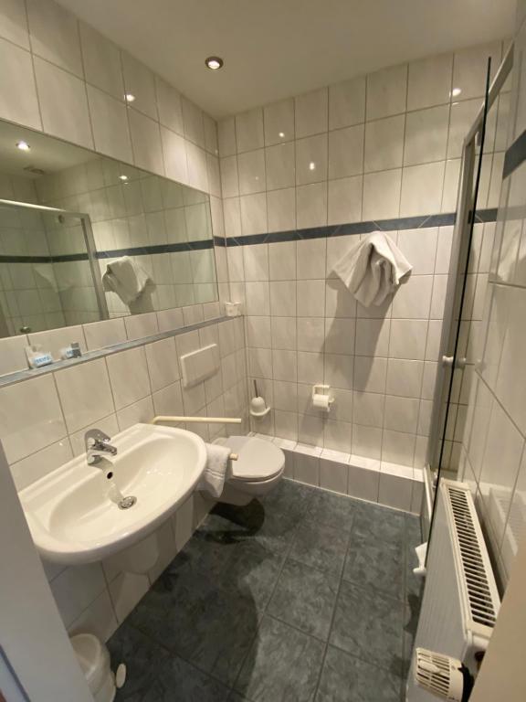 a bathroom with a sink and a toilet and a mirror at Hotel Montan in Duisburg