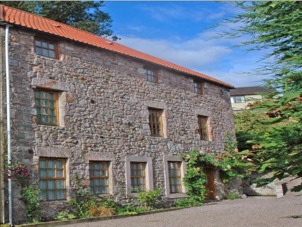 un edificio de piedra con ventanas laterales en The Old Mill, en Wooler