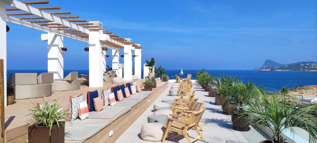 a row of chairs on a patio with the ocean in the background at Can Salia in San Antonio Bay
