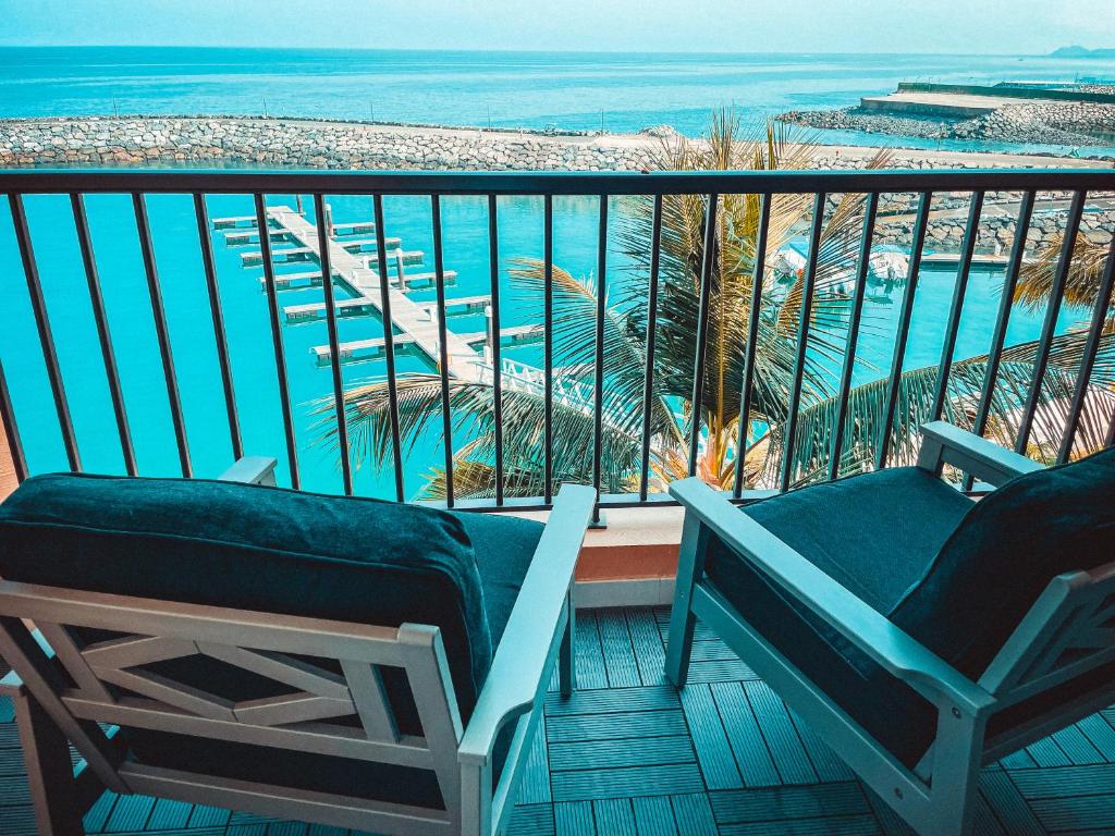 a balcony with two chairs and a view of the ocean at Mina AlFajer Apartments in Dibba