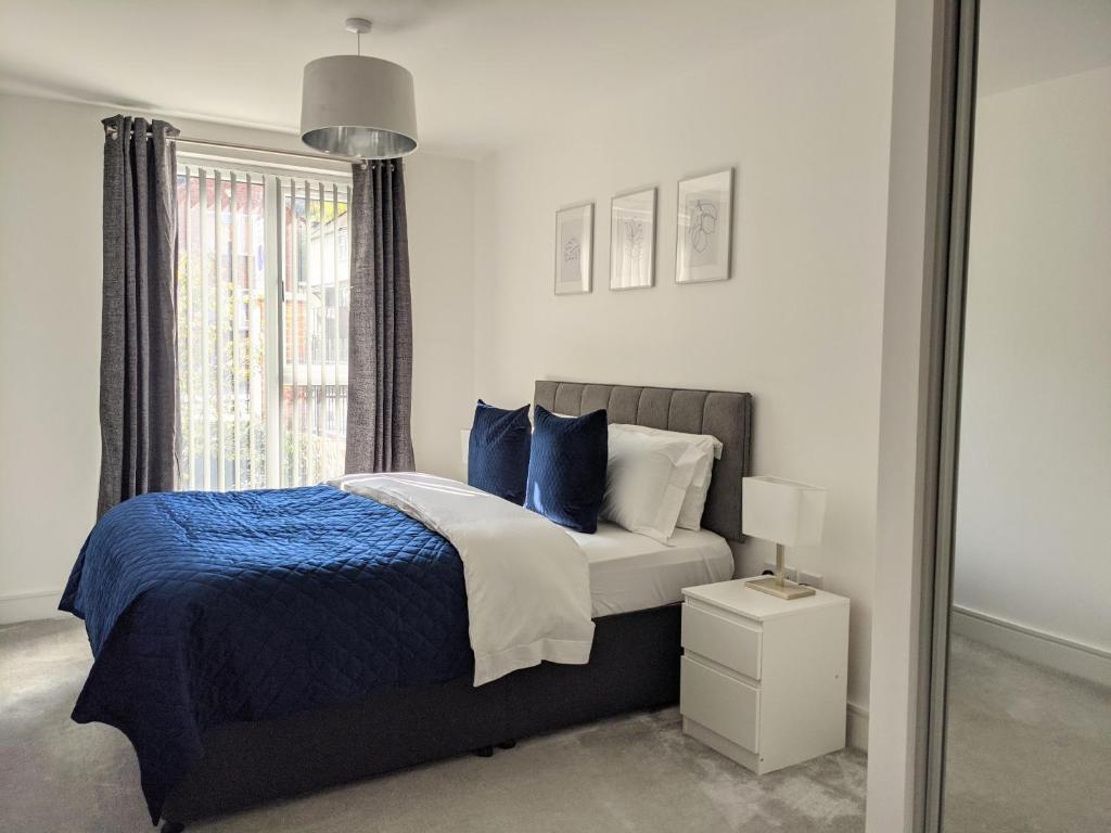 a bedroom with a bed with blue pillows and a window at Suffield Lodge by Wycombe Apartments in High Wycombe