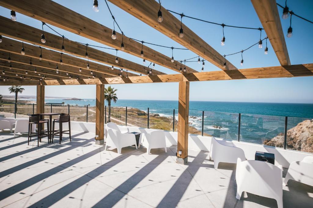 a patio with white chairs and a view of the ocean at MUTE Hostel Porto Covo in Porto Covo