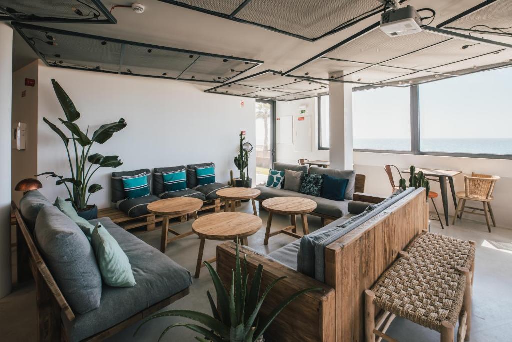 a living room with a couch and tables and chairs at MUTE Hostel Porto Covo in Porto Covo