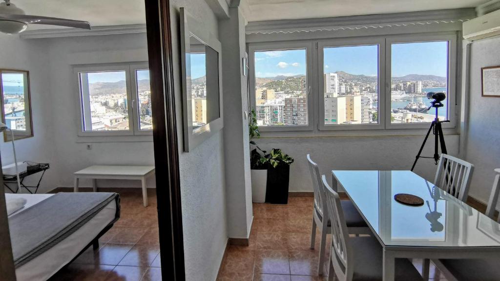 een woonkamer met een tafel, stoelen en ramen bij Mirador de Málaga in Málaga