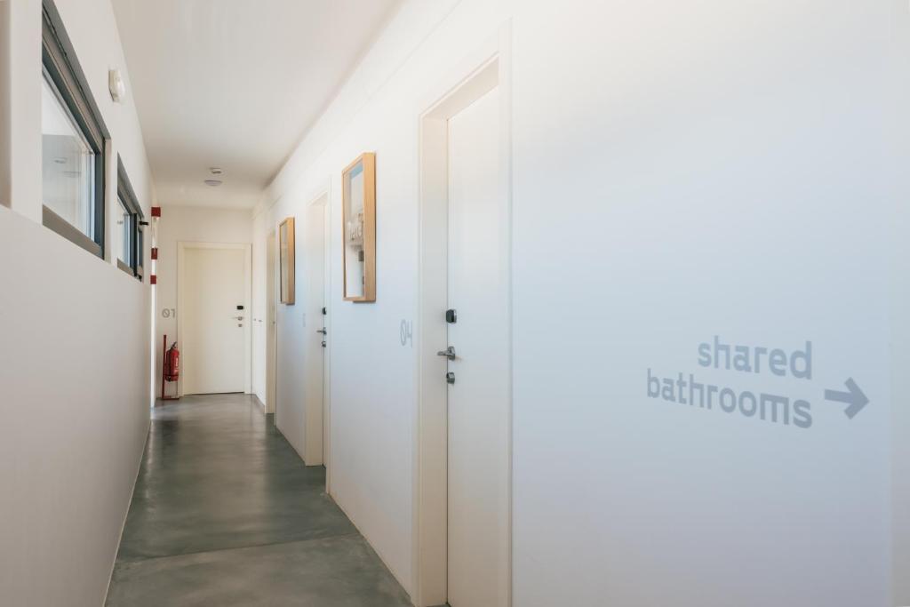 a hallway with white walls and white doors at MUTE Hostel Porto Covo in Porto Covo