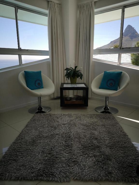 two chairs and a rug in a room with windows at Diamond House Guesthouse in Cape Town