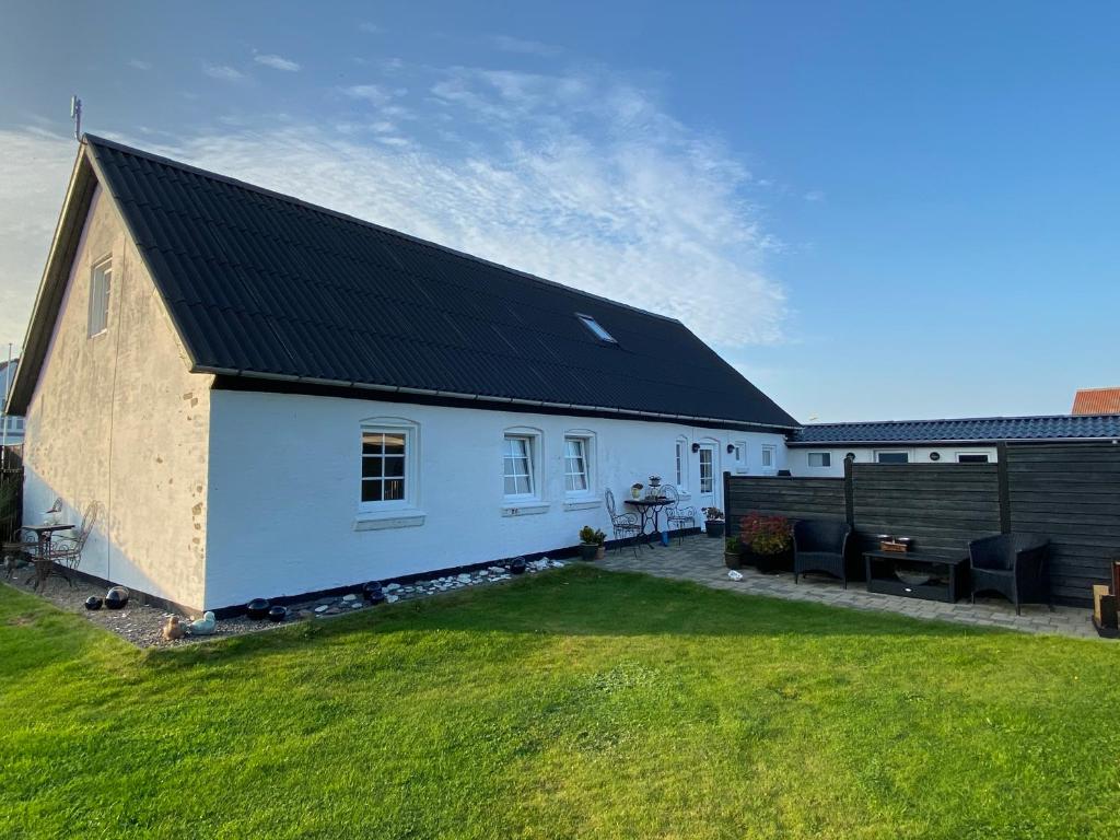 una casa blanca con techo negro y patio en A Vesterhav - tæt på 18b og hotel, en Harboør