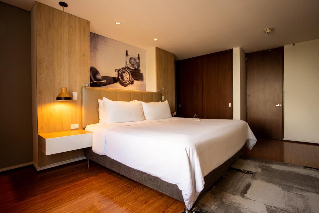 Quo Quality Hotel في مانيزاليس: غرفة نوم مع سرير أبيض كبير ودواليب خشبية