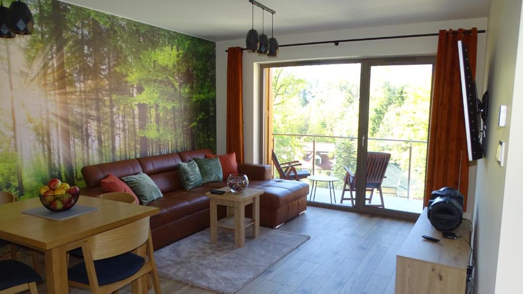 sala de estar con sofá de cuero y mesa en Apartament DeLux 2, en Szklarska Poręba