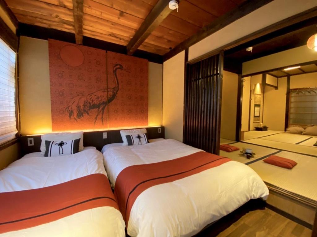 2 Betten in einem Zimmer mit Bild eines Vogels an der Wand in der Unterkunft Machiya Kikunoya in Nagoya
