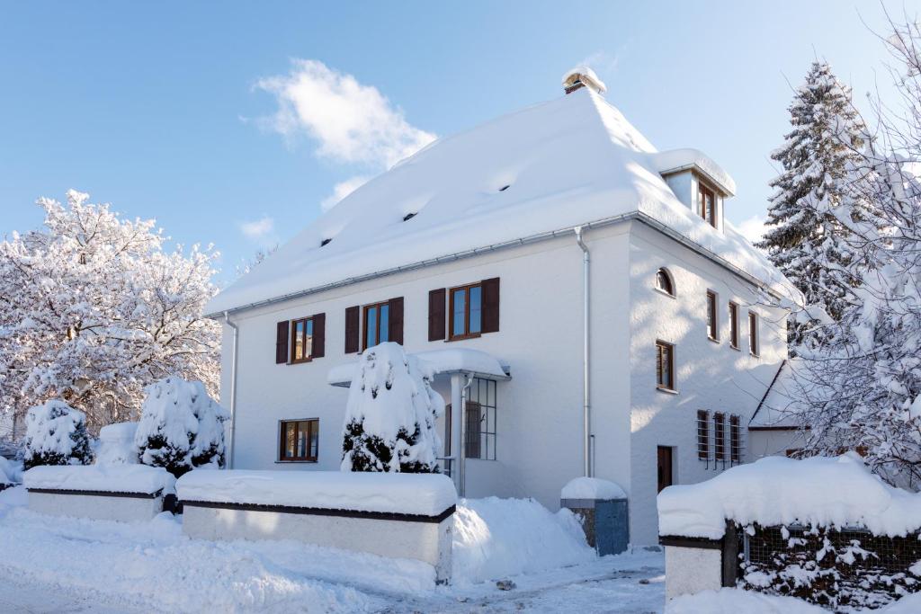 ein schneebedecktes weißes Haus in der Unterkunft Stadtvilla Falkenstein in Füssen