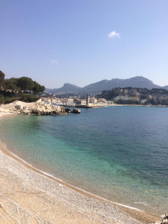 a beach with blue water and a bridge in the background at Le Galet de Cassis by K6&you in Cassis