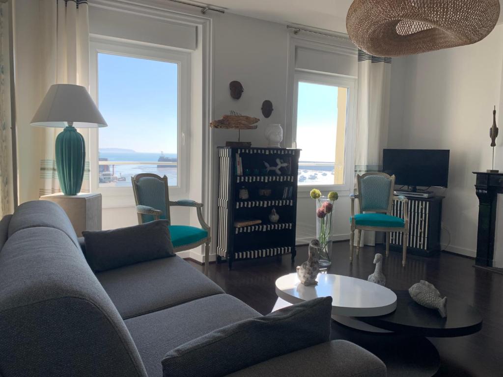 a living room with a couch and a table and windows at Appartement Villa Chausey, vue sur le port in Granville