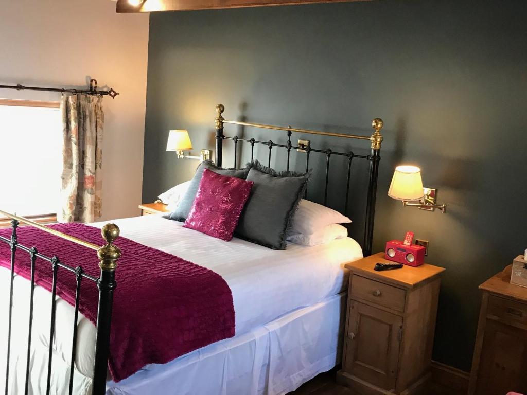 Schlafzimmer mit einem Bett mit lila Bettwäsche und Kissen in der Unterkunft Sebastians in Oswestry