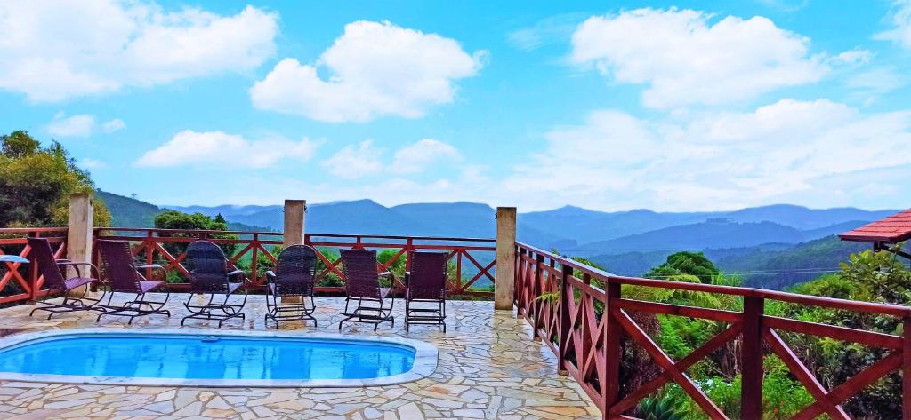 a patio with chairs and a swimming pool with mountains in the background at Pousada Nascer da Lua in Monte Verde