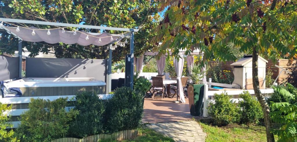 un jardin avec une pergola, une table et des chaises dans l'établissement Chez Monique et Jean-Claude, à Pézarches