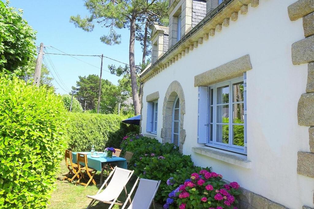une maison blanche avec des chaises, une table et des fleurs dans l'établissement Holiday Home in Carnac near Sandy Beach, à Carnac